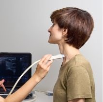 Kobieta z krótkimi włosami na badaniu USG tarczycy w gabinecie lekarskim