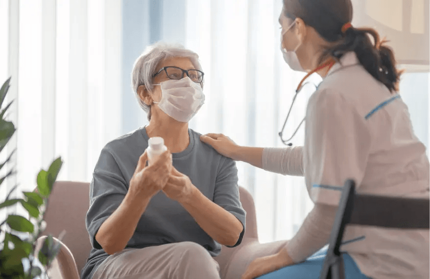 Pani doktor na wizycie domowej u pacjentki, wręczyła jej leki i trzyma dłoń na jej barku, wspierając w chorobie.